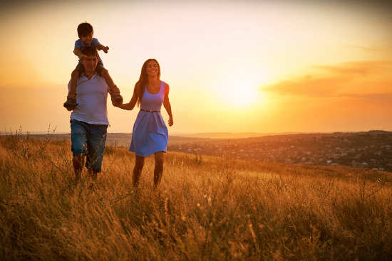 a man, woman and child walking through a field