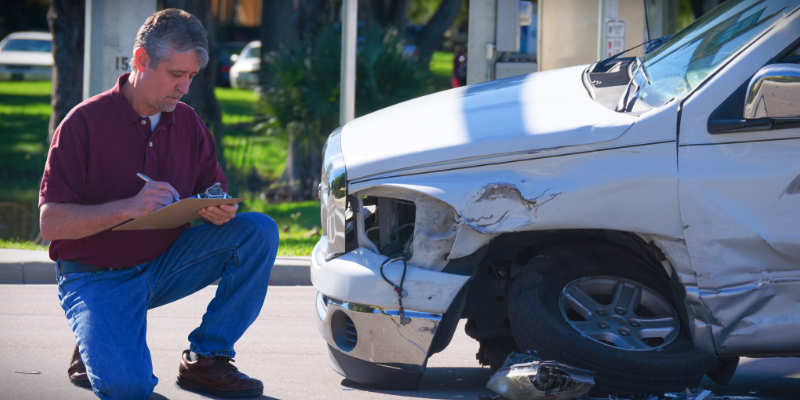 man looking at dented car